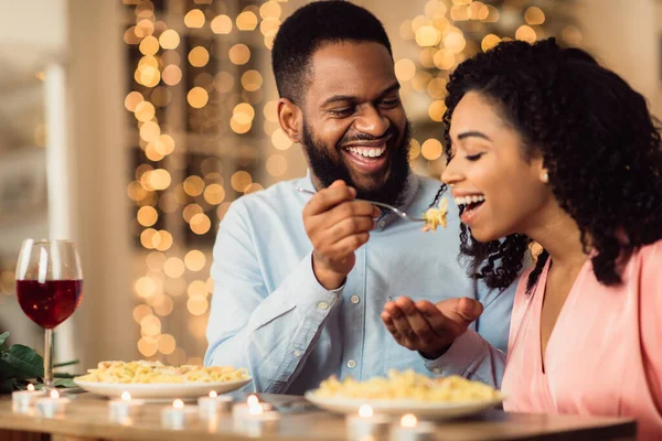 Uśmiechnięty czarny mężczyzna karmi swoją kobietę na randce — Zdjęcie stockowe