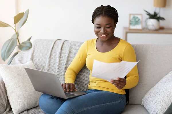 Carreira Freelance. Senhora negra positiva trabalhando com papéis e laptop em casa — Fotografia de Stock