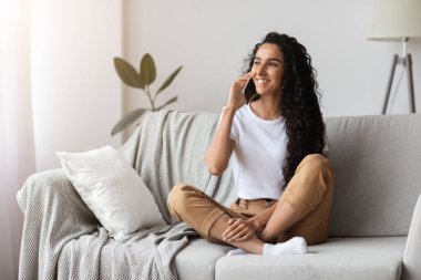 Mutlu esmer kadın telefonda konuşuyor.