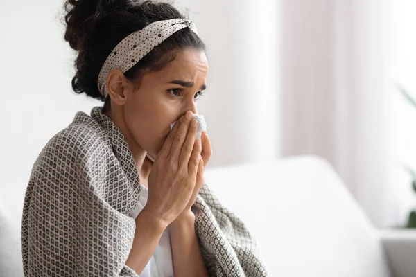 Sick woman covered in blanket sneezing her nose — Stock Photo, Image