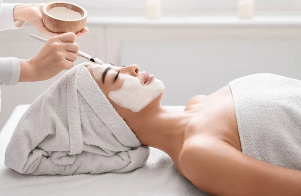 Beautician Anwendung Ton Gesichtsmaske auf schöne asiatische Frau in Wellness-Salon — Stockfoto