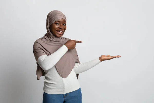 Check This. Excited Black Woman In Hijab Pointing At Her Empty Palm — Stock Photo, Image