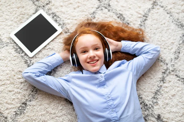 Chica feliz acostada en la alfombra del suelo, escuchando música —  Fotos de Stock