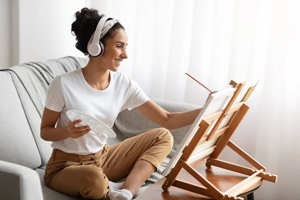 Joyful woman listening to music and drawing