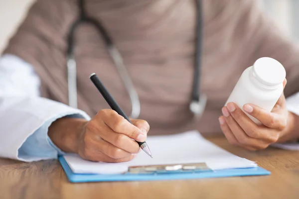 Ärztin hält Medizin in der Hand, schreibt Rezept in Arztkarte — Stockfoto