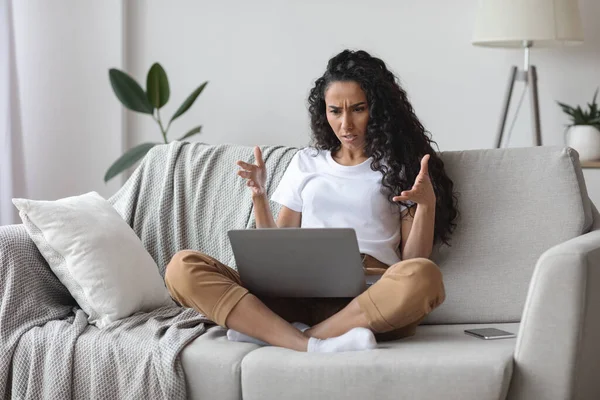 Angry woman looking at laptop screen and gesturing — Stock Photo, Image
