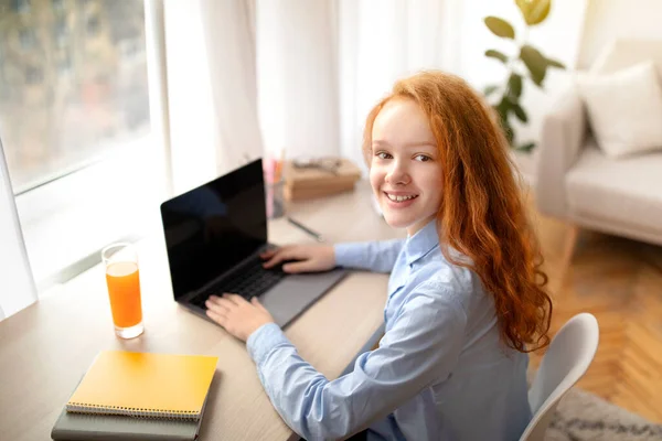Dizüstü bilgisayarını para kazanmak için kullanan kız, kameraya bakıyor. — Stok fotoğraf