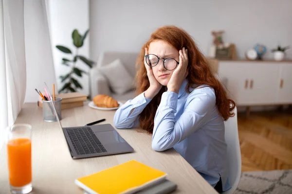 Müdes Mädchen sitzt mit Laptop am Schreibtisch — Stockfoto