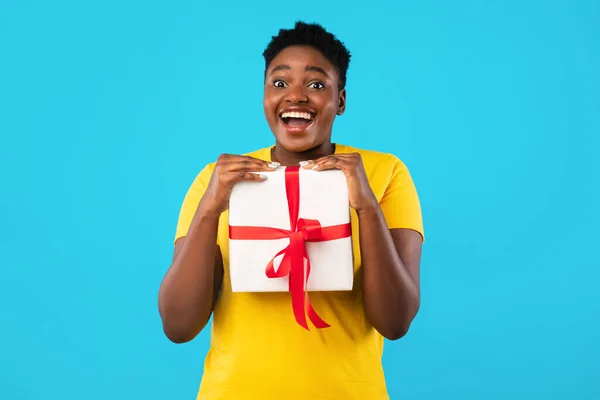 Vrolijke oversized Afrikaanse vrouw met geschenken doos op blauwe achtergrond — Stockfoto