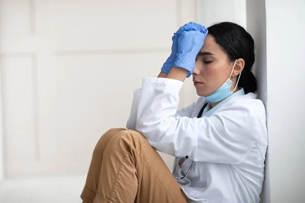 Exhausted brunette woman doctor having difficult day at clinic