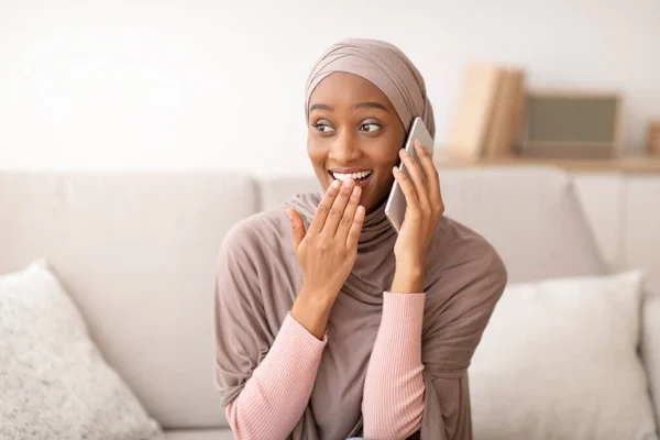 Modern kommunikációs koncepció. Meglepett muszlim nő hidzsáb beszél mobilon otthon, csevegés online barátjával — Stock Fotó