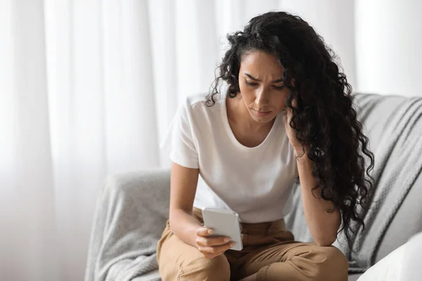 Upset woman looking at mobile phone screen, home interior — Stock Photo, Image