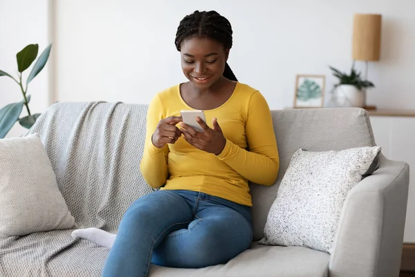 Χρήσιμη εφαρμογή. Νεαρή μαύρη χιλιετή γυναίκα χαλαρώνοντας στο σπίτι με Smartphone — Φωτογραφία Αρχείου