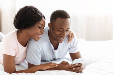 Neşeli Afrikalı Amerikalı çift akıllı telefondan uygulama kullanıyor.