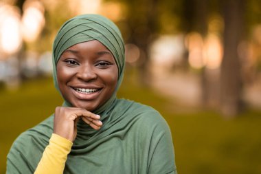 Neşeli Afrikalı Müslüman kadın tesettürde poz veriyor, kameraya gülümsüyor.