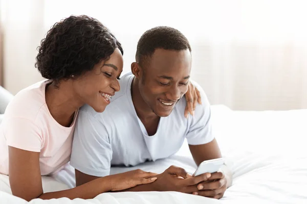 Radosna afrykańska para używa aplikacji razem na smartfonie — Zdjęcie stockowe