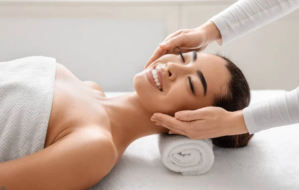 Mulher coreana sorridente no salão de spa desfrutando de relaxante massagem na cabeça — Fotografia de Stock