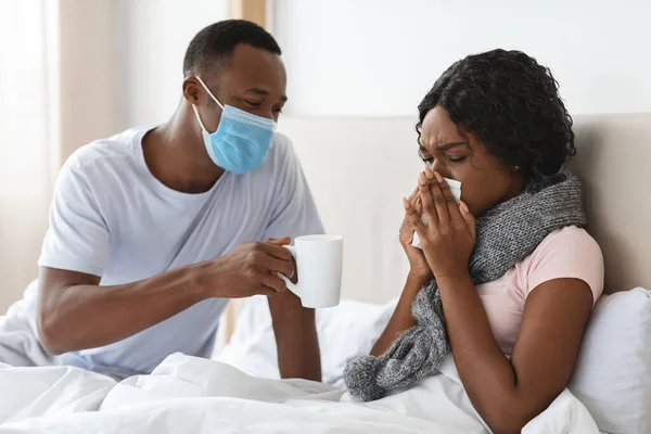 Svart man i ansiktsmask ta hand om sjuk fru — Stockfoto