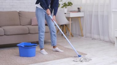 Evi temizliyorum. Tanınmayan ev hanımı paspas ve kovayla yerleri yıkıyor.