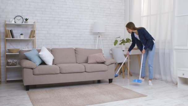 Jovem mulher varrendo chão em casa, coletando poeira para colher, câmera lenta — Vídeo de Stock