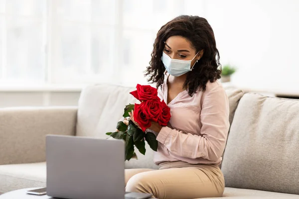 온라인 데이트를 하고 장미를 들고 의료용 마스크를 쓴 흑인 여성 — 스톡 사진