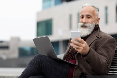 Dışarıda akıllı telefon kullanan üst düzey bir iş adamı.