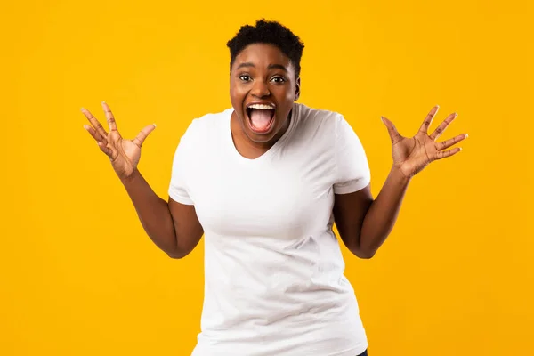 Plus-Size mulher africana gritando em emoção posando em fundo amarelo — Fotografia de Stock