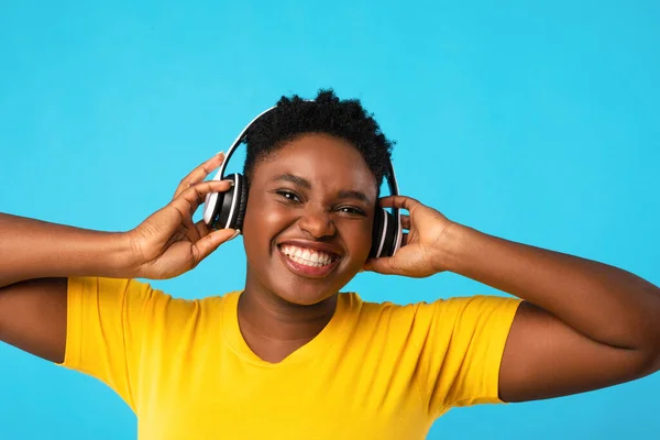 Μαύρη γυναίκα που φοράει ακουστικά ακούγοντας μουσική πάνω από το μπλε φόντο — Φωτογραφία Αρχείου