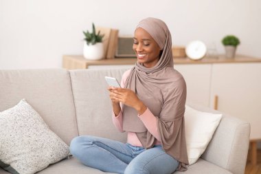 Bin yıllık Müslüman kadın tesettürde cep telefonunu iş için, iletişim için ya da evdeki rahat koltukta ders çalışmak için kullanıyor.