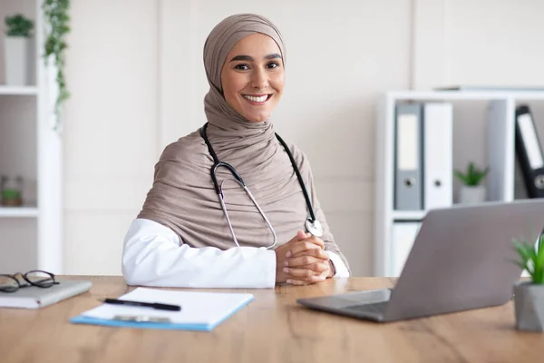 Mujer sonriente doctora musulmana posando en su gabinete —  Fotos de Stock