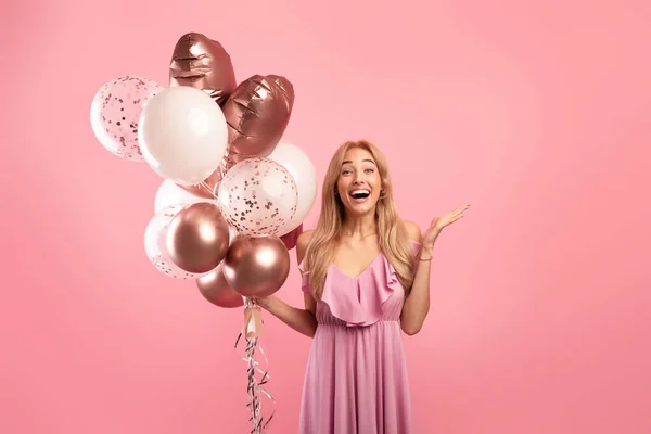 Portrait de jeune femme excitée avec un bouquet de ballons pour l'anniversaire ou la journée des femmes, célébrant des vacances sur fond rose — Photo