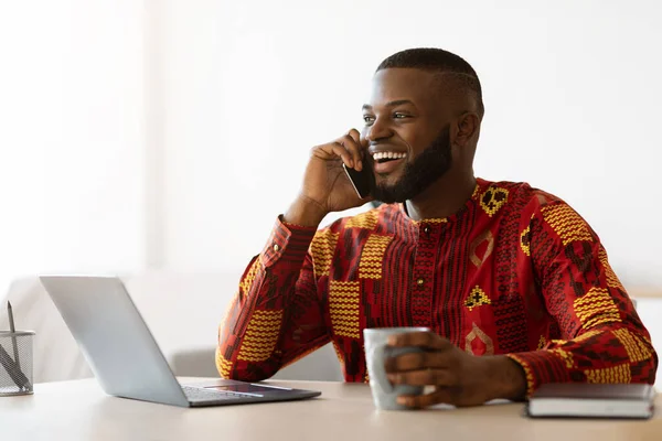 Africano freelancer chico hablando en el teléfono celular y disfrutando de café en el Ministerio del Interior —  Fotos de Stock