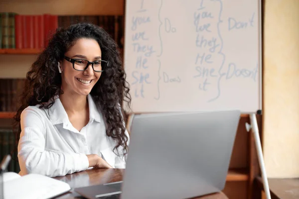 Englischlehrer sitzt am Schreibtisch und erklärt Schülern den Unterricht — Stockfoto