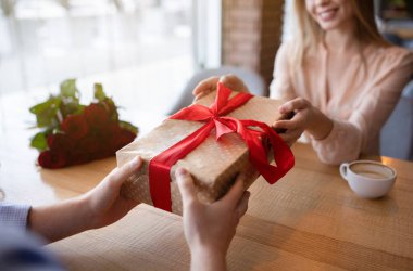 Romantik bir genç adamın sevgilisine şehir kafesinde sevgililer günü hediyesi vermesi.