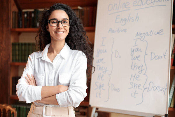 English teacher standing at whiteboard, posing at camera