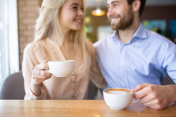 Romántica pareja milenaria bebiendo café y mirándose el uno al otro en la acogedora cafetería, enfoque selectivo —  Fotos de Stock