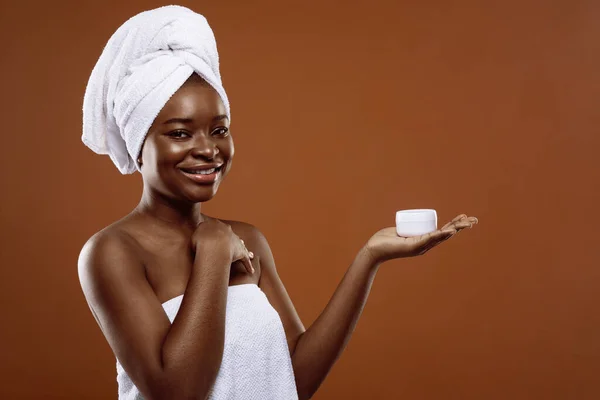 护肤化妆品。年轻美丽的黑人女人手里拿着一罐保湿霜 — 图库照片