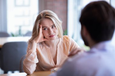 Young Caucasian woman disinterested in blind date, feeling bored with conversation at city cafe clipart