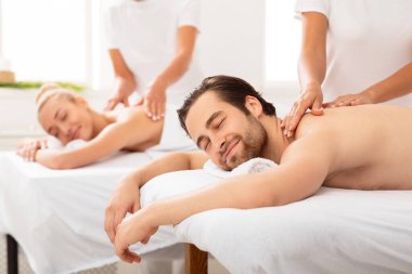 Rahatlamış karı koca sırt masajı alıyor. Kapalı alanda uzanıyor.