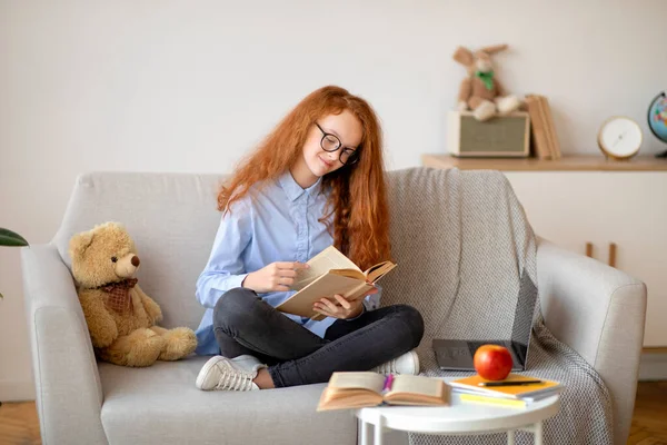 女の子は眼鏡をかけ、床に座って本を読む — ストック写真