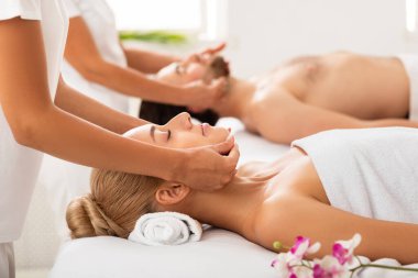 Rahatlamış eşler yüz masajı yaptırıyor. Yataklarda uzanıyorlar.