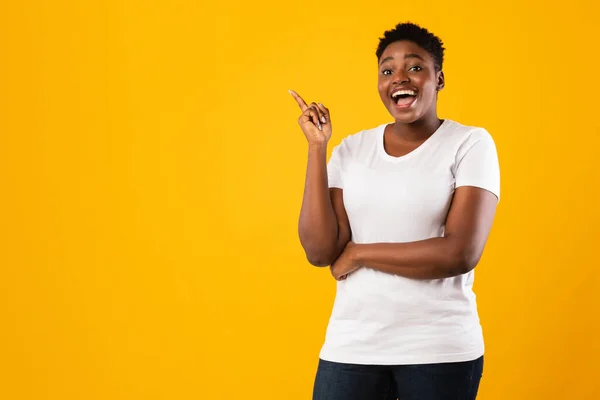 Dama negra señalando con el dedo hacia arriba teniendo idea sobre fondo amarillo — Foto de Stock