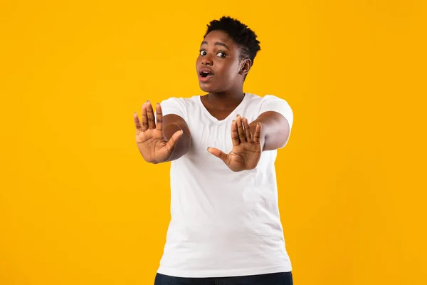 Afrikanerin gestikuliert mit beiden Händen, gelber Hintergrund — Stockfoto