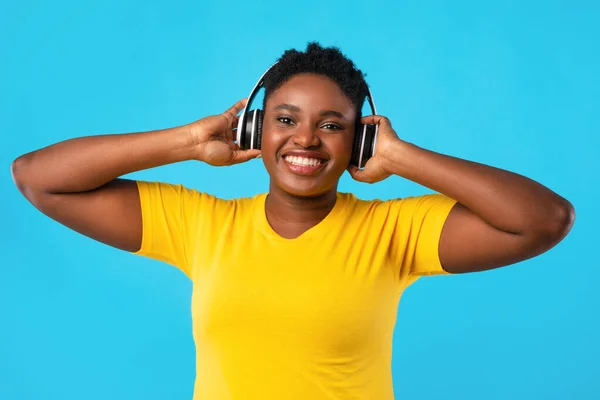 Afrikai nő hallgat zenét viselő vezeték nélküli fejhallgató kék háttér — Stock Fotó