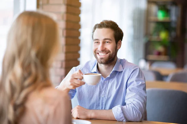 Sonriente millennial chico bebiendo café con su novia en la cafetería, tener una conversación divertida durante el desayuno —  Fotos de Stock