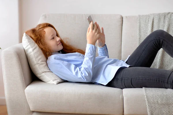 Fille à l'aide de son téléphone portable se détendre sur le canapé — Photo