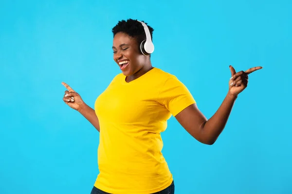 黑人超重女士听音乐在蓝色工作室的背景下跳舞 — 图库照片