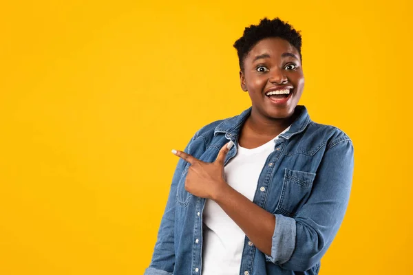 Femme afro-américaine excitée pointant du doigt sur fond jaune — Photo