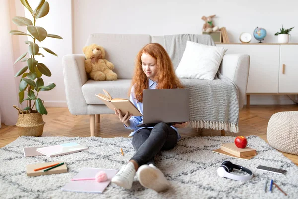 女孩坐在地板上看书，用手提电脑 — 图库照片
