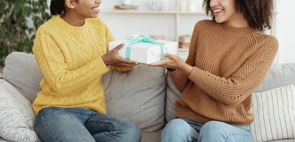 Compartilhando presente de férias, congratulando-se com o aniversário. Sorrindo afro-americana dando presente ao amigo — Fotografia de Stock